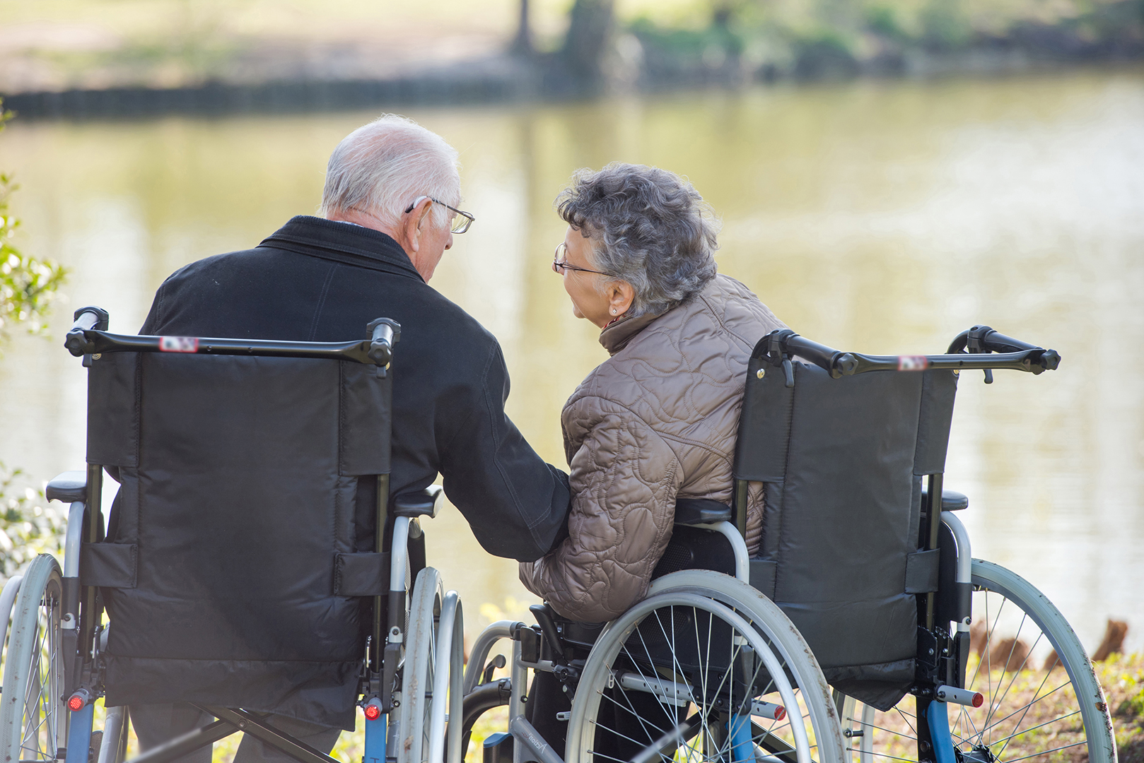 Verliebte Senioren am See im Rollstuhl